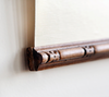 a close-up view of a wooden frame with intricate carvings, mounted on a white wall.